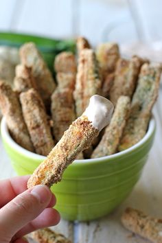 a hand holding a piece of food in a green bowl with some kind of stick sticking out of it