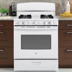 a white stove top oven sitting in a kitchen next to wooden cabinets and counter tops