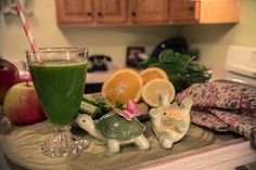 an assortment of fruits and vegetables on a kitchen counter with a glass of green juice