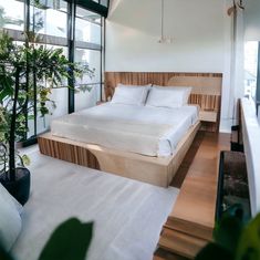 a large bed sitting in the middle of a bedroom next to a tall glass window