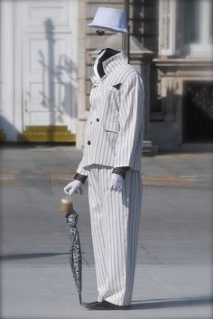 a man in a white suit and hat holding an umbrella