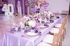 the table is set up with purple and white flowers, plates and silverware on it