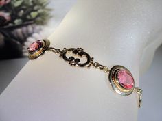 "This is a beautiful rose pink bracelet that is 14k Gold Filled. There are 4 oval cut faceted rosy pink glass gems with a decorative scroll link in between each. The look is stunning! Size of the bracelet is 7.25 inches. It has a round twist closure and a safety chain that is also able to be released and attached with the same type of closure. *Hang Tag reads: AMCO, 1/20 14K Gold Filled *Length is 7.25 inches *Width is .5 inches *Condition is Excellent = in \"LIKE NEW\" Condition; Pre-owned To v Pink Bangle For Formal Occasions, Pink Formal Bangle Jewelry, Elegant Rose Gold Bracelet For Formal Occasions, Antique Hallmarked Pink Jewelry, Elegant Pink Gold Bracelet For Formal Occasions, Pink Round Antique Jewelry, Antique Pink Round Jewelry, Pink Antique Hallmarked Jewelry, Antique Pink Hallmarked Jewelry