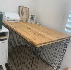 a dog kennel with a wooden top and metal cage on the floor next to it