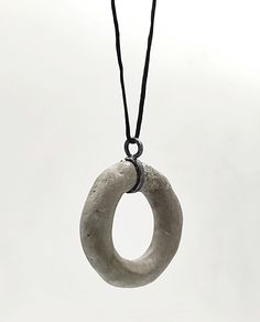 This concrete  pendant long Necklace is a unique and stunning piece of handmade jewelry that combines modern and artistic style The pendant's shape  is irregular round and open made of  concrete. Τhe pendant is passed on a black synthetic cord,with a handcrafted oxidized silver hook clasp.  A unique and elegant accessory perfect for both casual and formal occasions. In contact with skin, moisture and air, concrete becomes darker. Αs each piece is individually handmade, slight variations in  text Minimalist Hand Cast Jewelry With Round Pendant, Minimalist Soldered Pendant Jewelry, Modern Handmade Circular Necklace, Cement Jewelry, Concrete Necklace, Concrete Pendant, Concrete Jewelry, Artistic Style, Hook Clasp