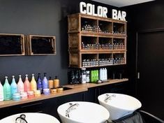 two white sinks sitting next to each other in front of a counter filled with bottles