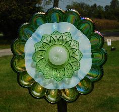 a green and white flower shaped object on top of a metal pole in the grass