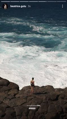 a woman standing on top of a rocky beach next to the ocean