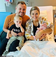 a man, woman and child sitting on a hospital bed