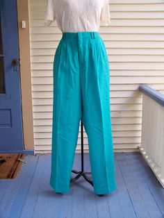 "Pleated-front trousers were popular during the 1980s. As you can see in the 2nd picture, the trousers have 4 - 6 pleats in the front for a very loose and flowy fit. The waist is at the natural waist above the hips. The tight waistline and flowy trousers make the waist seem smaller. The looseness of the trousers covers any lumps and bumps. These trousers pair well with the flowy 1980s tops. Check those out in this store. These 1980s vintage trousers are made of a Polyester/Rayon blend in Jade Gr Retro Pleated Bottoms For Workwear, Vintage Formal Spring Pants, Retro Pleated Workwear Bottoms, Vintage Pleated Bottoms For Work, Retro Full-length Green Bottoms, Retro Green Pleated Bottoms, Vintage Green Wide-leg Bottoms, Green Full-length Pants With Hip Pockets, Green Wide-leg Bottoms With Elastic Waistband