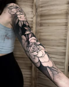 a woman's arm with black and white flowers on the left side of her arm