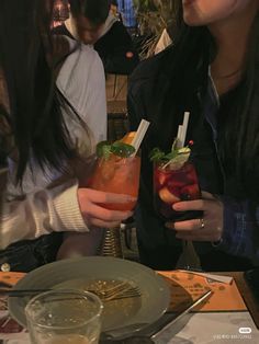 two women holding up drinks at a table