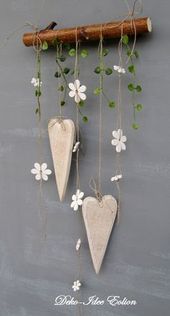 three wooden hearts hanging from a branch with white flowers and greenery attached to them