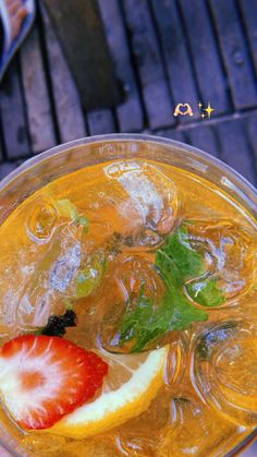 a person holding a drink with fruit on the rim and mint garnish in it