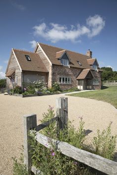 a large brick house sitting on top of a lush green field next to a wooden fence