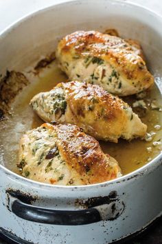 three pieces of chicken in a pan with broth