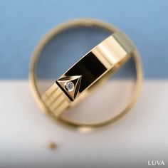 a gold ring with a diamond in it sitting on a white countertop next to a blue wall