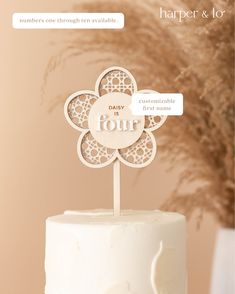 a white cake topped with a wooden cut out of a flower on top of a table