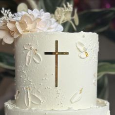 a white cake with flowers and a cross on top