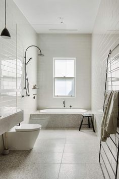 a large white bathroom with two sinks and a bathtub in the middle of it