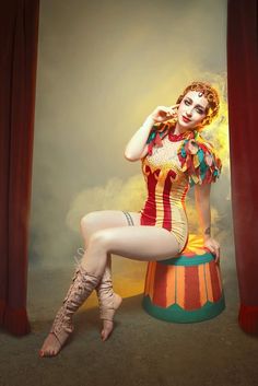 a woman dressed as a clown sitting on top of a barrel