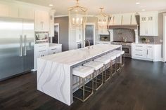 a large kitchen with marble counter tops and white cabinets, along with stainless steel appliances