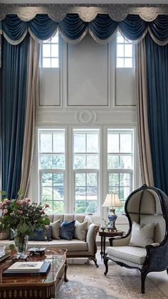 an elegant living room with blue drapes and white couches in front of large windows