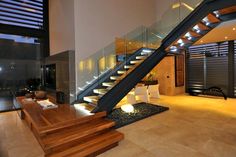 an open living room with stairs leading up to the second floor and glass railings