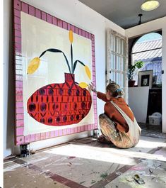 a woman is painting a vase on the wall