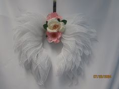 a white feather wreath with pink and white flowers