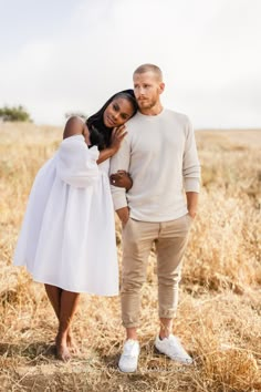 a man and woman standing in the middle of a field