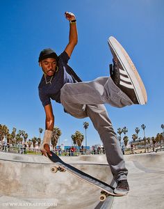 a young man riding a skateboard up the side of a cement ramp at a skate park