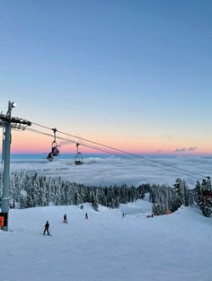 skiers are skiing down the snowy slopes at sunset, with a ski lift in the background