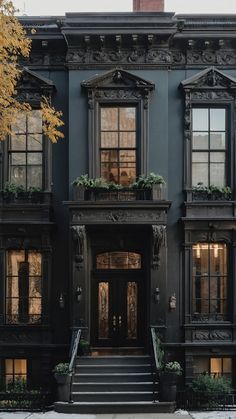 an old black building with many windows and plants on the front door, along with steps leading up to it