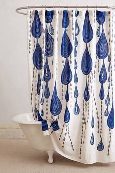 a shower curtain with blue water drops hanging from it's side in front of a white bathtub