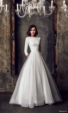 a woman in a white wedding dress standing next to a chandelier