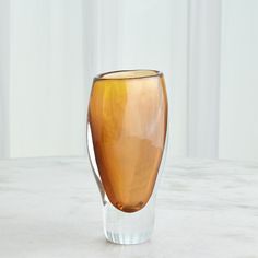 an orange glass vase sitting on top of a white marble countertop next to a wall