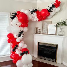 the balloon arch is decorated with red, white and black balloons in front of a fireplace