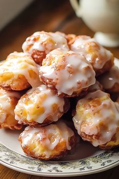 a plate full of glazed donuts sitting on a wooden table next to a cup