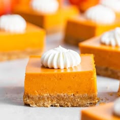 several slices of pumpkin cheesecake with whipped cream on top, sitting next to each other