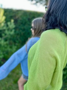 two girls are playing with a frisbee in the grass outside on a sunny day