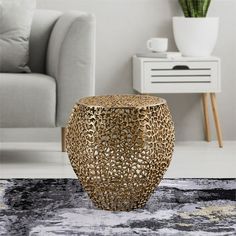 a gold vase sitting on top of a rug in front of a white couch and table