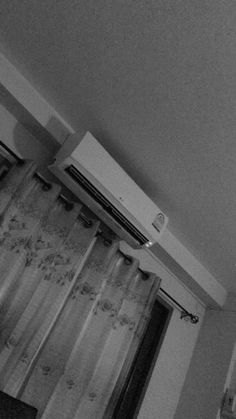 a black and white photo of an air conditioner on the wall above a window