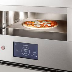 a pizza sitting on top of a metal counter in an oven with it's door open