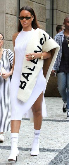 a woman is walking down the street wearing a white dress with black letters on it