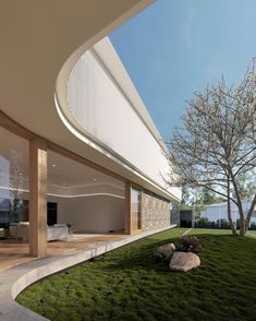 the interior of a modern house with grass and rocks on the ground in front of it