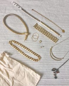 several different types of jewelry laid out on a bed sheet, including necklaces and bracelets