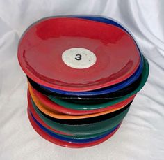 a stack of colorful plates sitting on top of a white cloth covered table next to each other