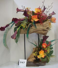 an arrangement of flowers is displayed on a stand