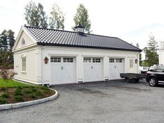 a car parked in front of a white garage with two doors on the side of it